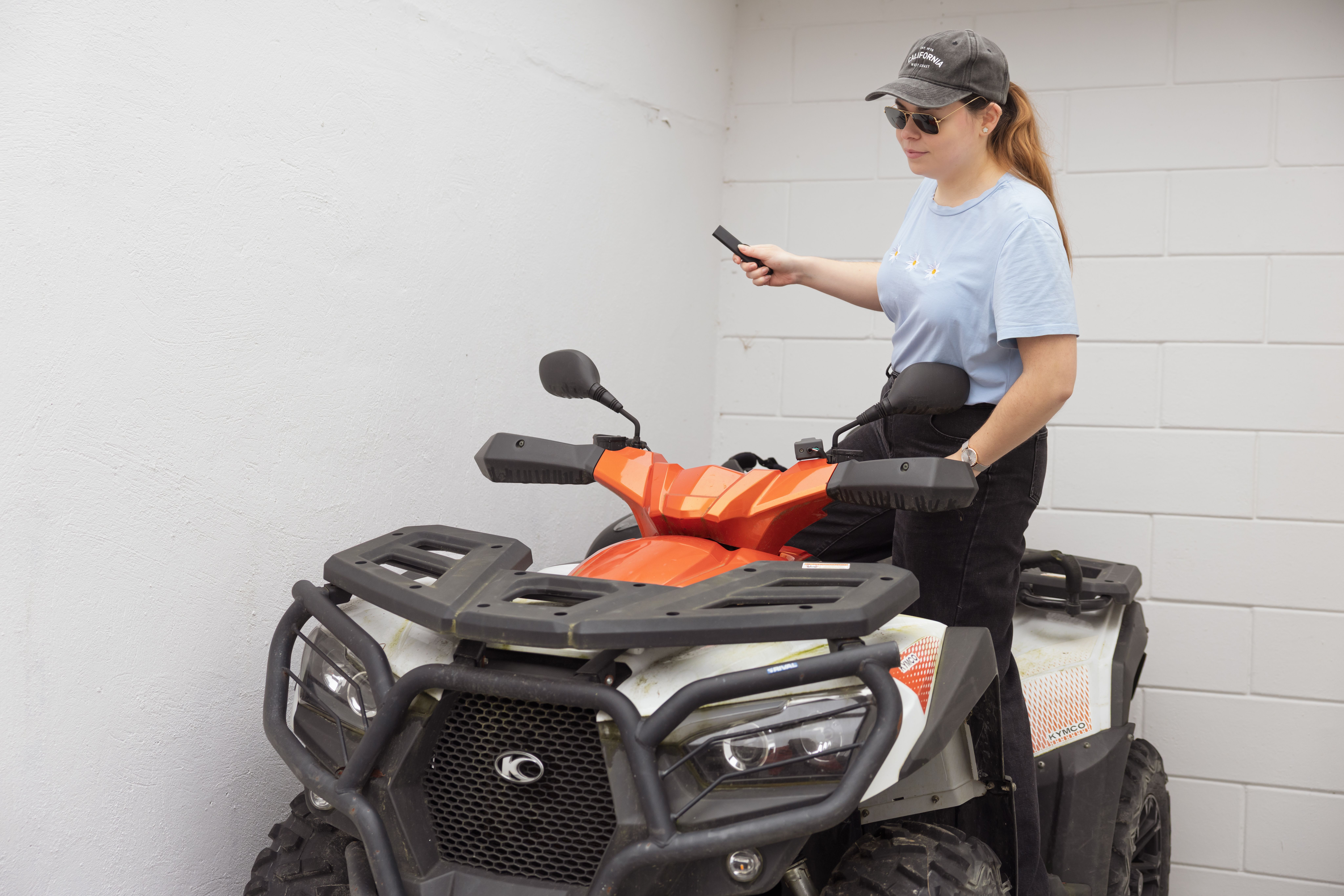 A woman prepares to hide a Tracker GPS Classic inside an ATV (quad).